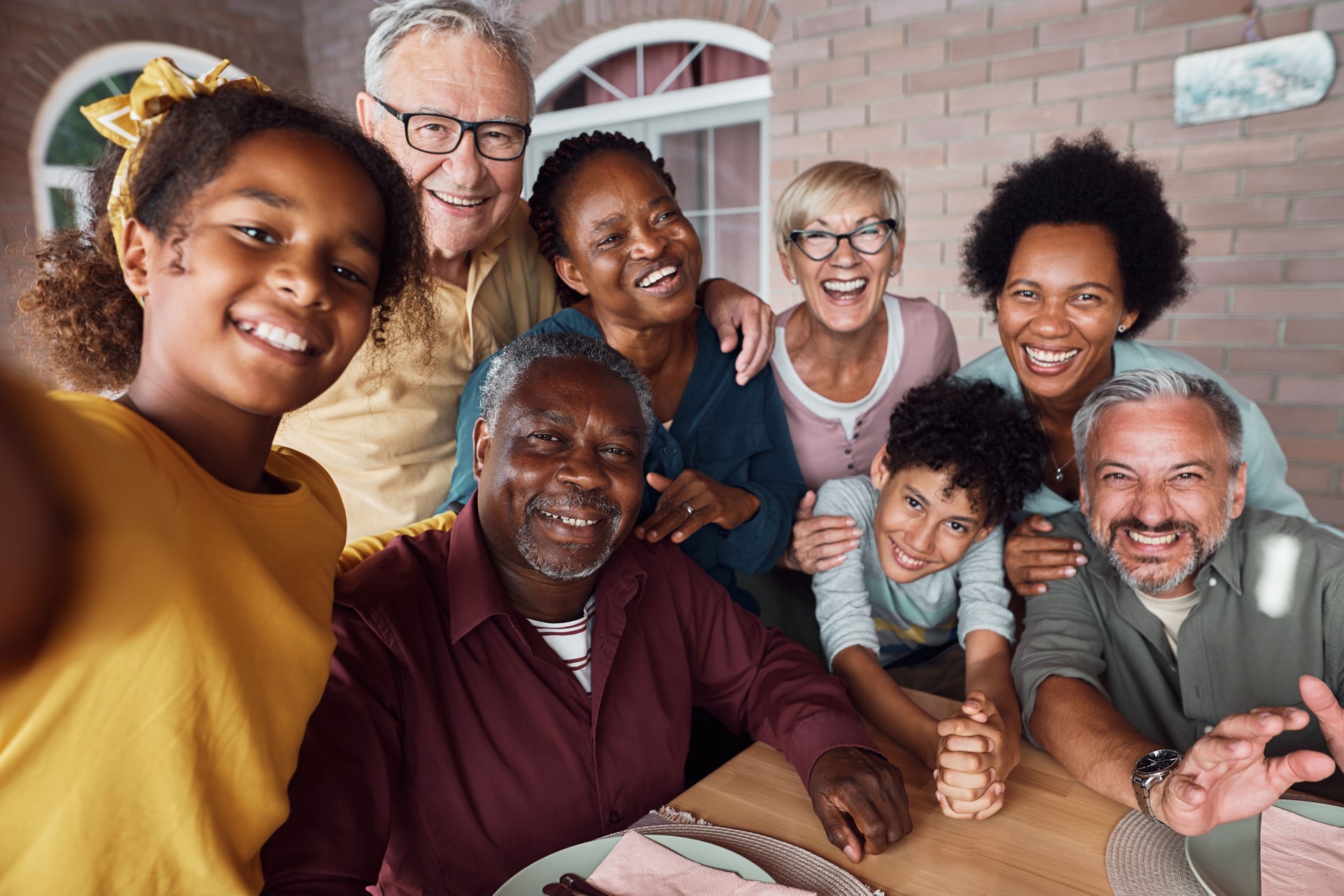 Happy multiracial extended family having fun while taking selfie on a patio.
